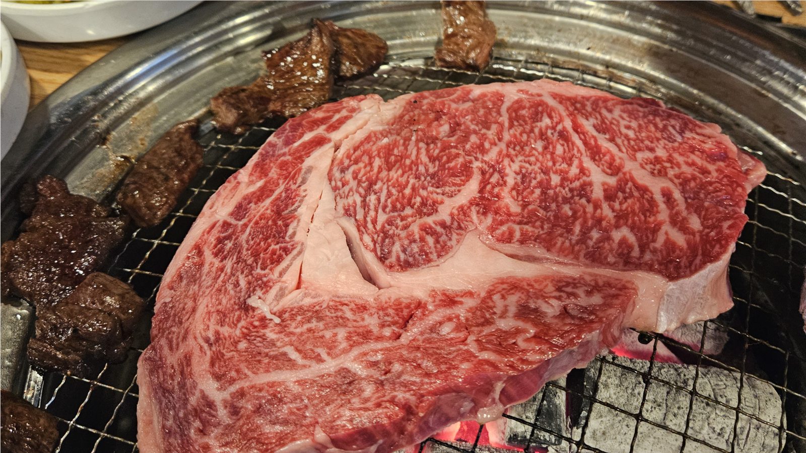 Highly marbled Hanwoo cooking over charcoal at a table restaurant near Majang Meat Market