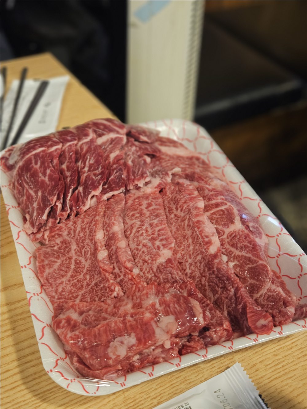Several raw marbled Hanwoo cuts arranged on a tray before charcoal grilling